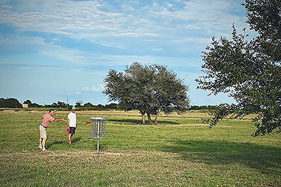 Two men playing disc golf at Lake Dewberry RV Resort's 9-hole disc golf course