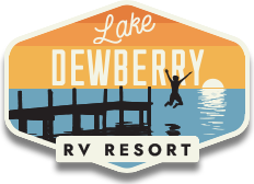 Lake Dewberry RV Resort Logo: Illustrated silhouette of a boy jumping off a dock into a lake as the sun sets over the water